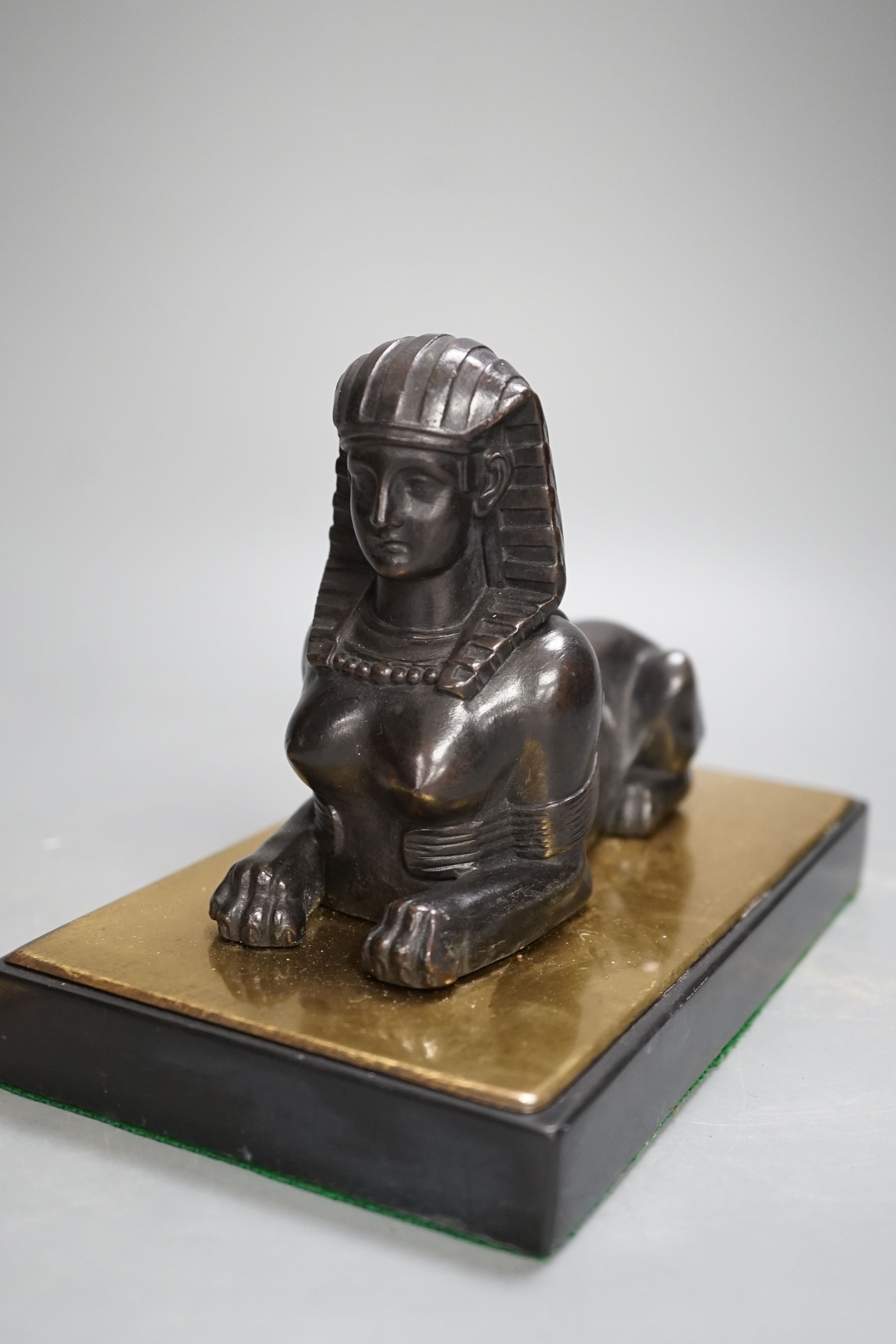 A patinated metal model of a sphinx and a bronze and gilt figure of a Nubian man. 22cm